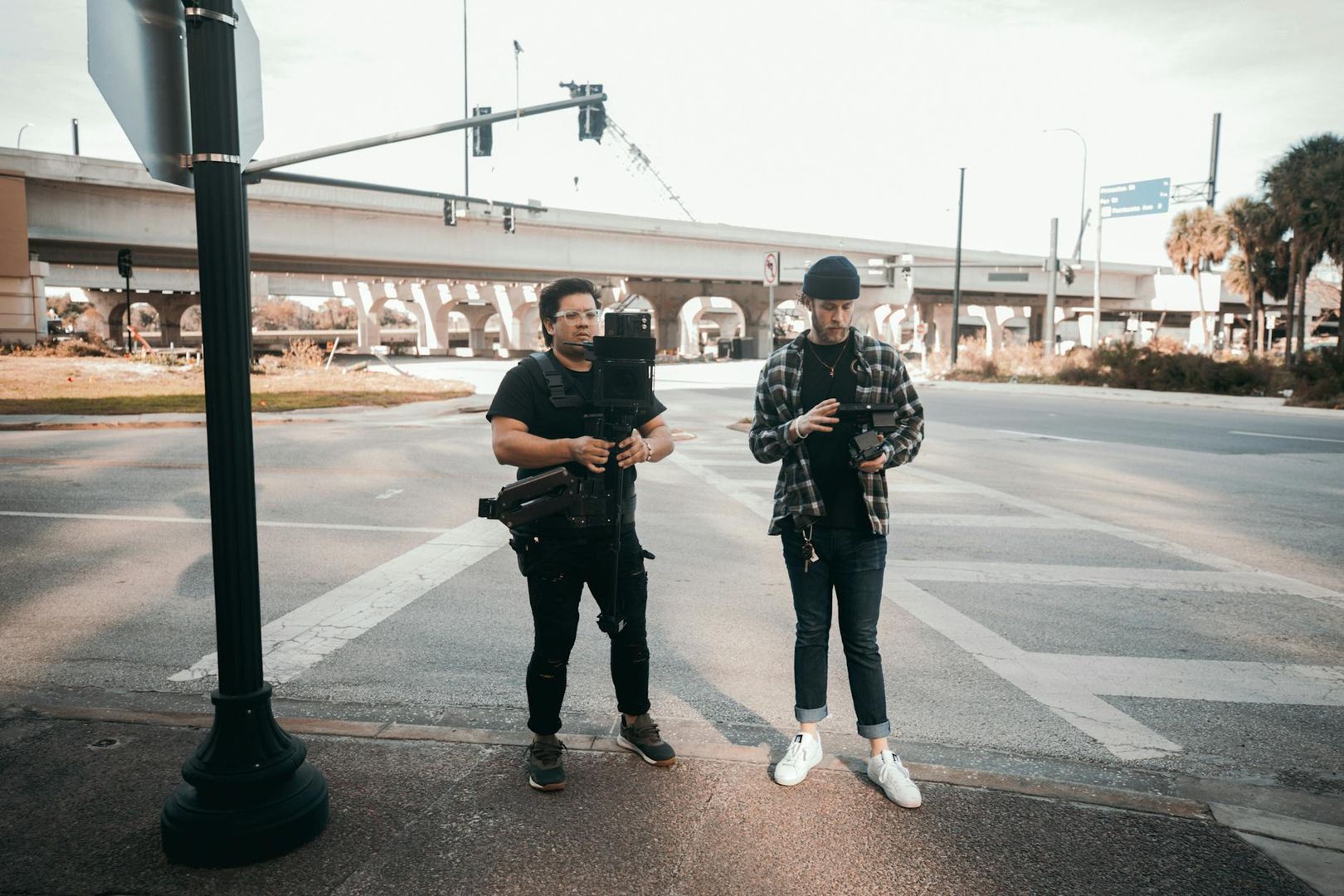 Två män från ett produktionsbolag förbereder filmutrustning vid en stadskorsning.